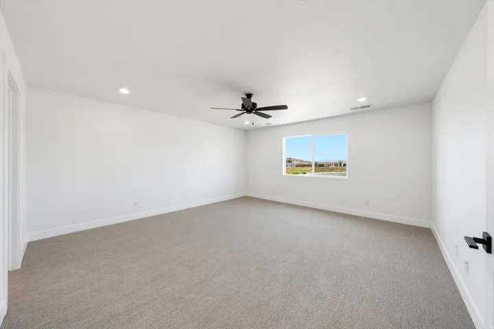 Spacious room featuring neutral carpeting, white walls, recessed lighting, and a ceiling fan