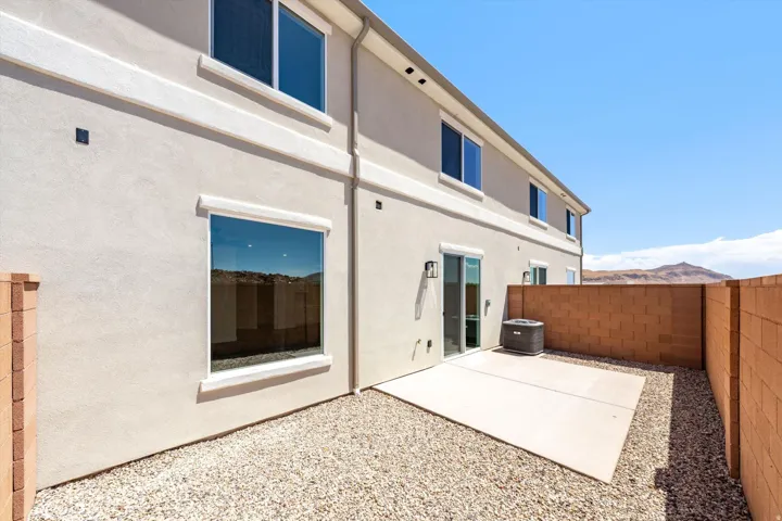 Private patio area with concrete slab, gravel landscaping, and block wall fencing