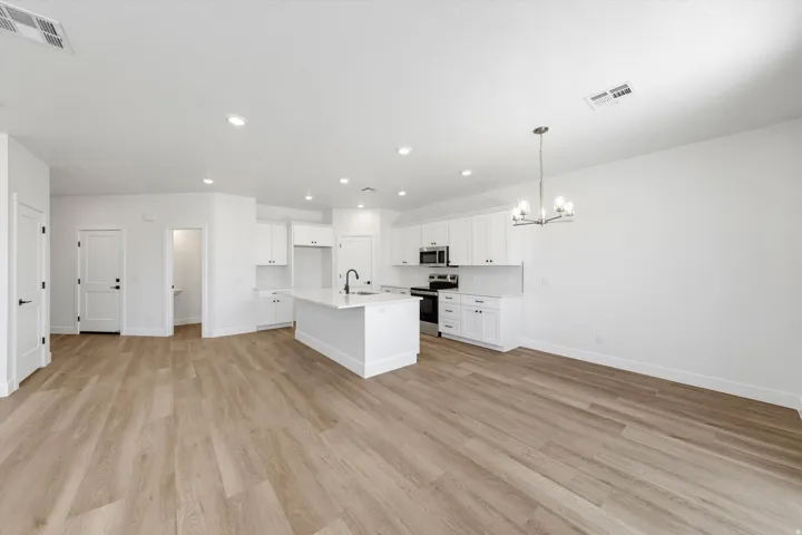 Open-concept living space with wood-finish flooring, recessed lighting, and a modern chandelier