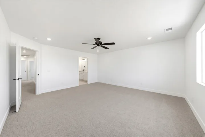 Spacious room featuring neutral carpeting, a ceiling fan, recessed lighting, and a window for natural light