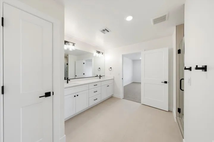 White double vanity with dual sinks, extensive countertop space, and under-cabinet storage