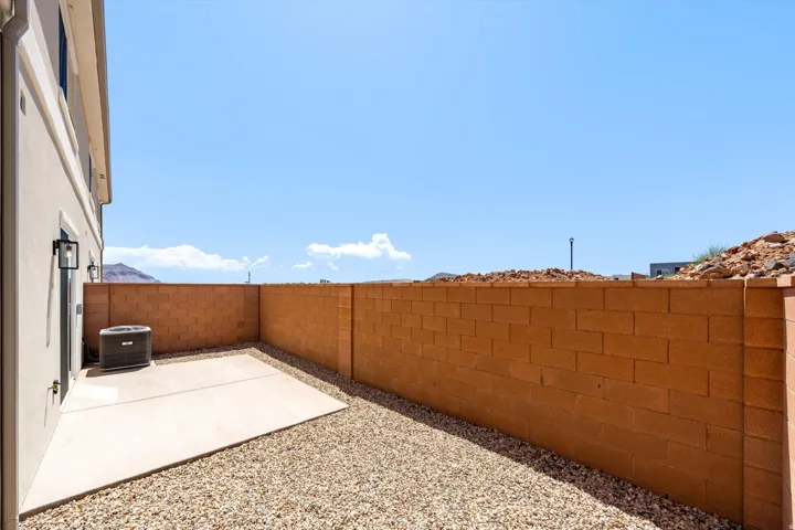Private courtyard featuring a concrete patio, gravel landscaping, and a block wall perimeter