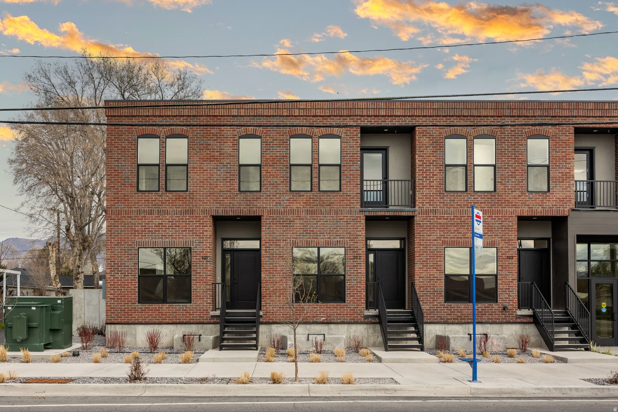 Brick exterior construction, multiple private balconies, ground-level entryways, and modern black-framed windows
