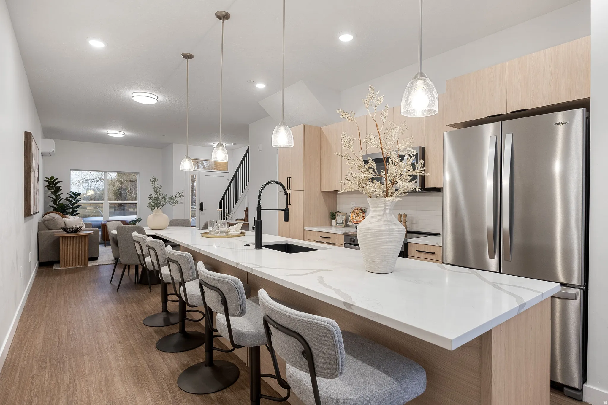 Kitchen island with white countertop, integrated sink, pendant lighting, and stainless steel appliances