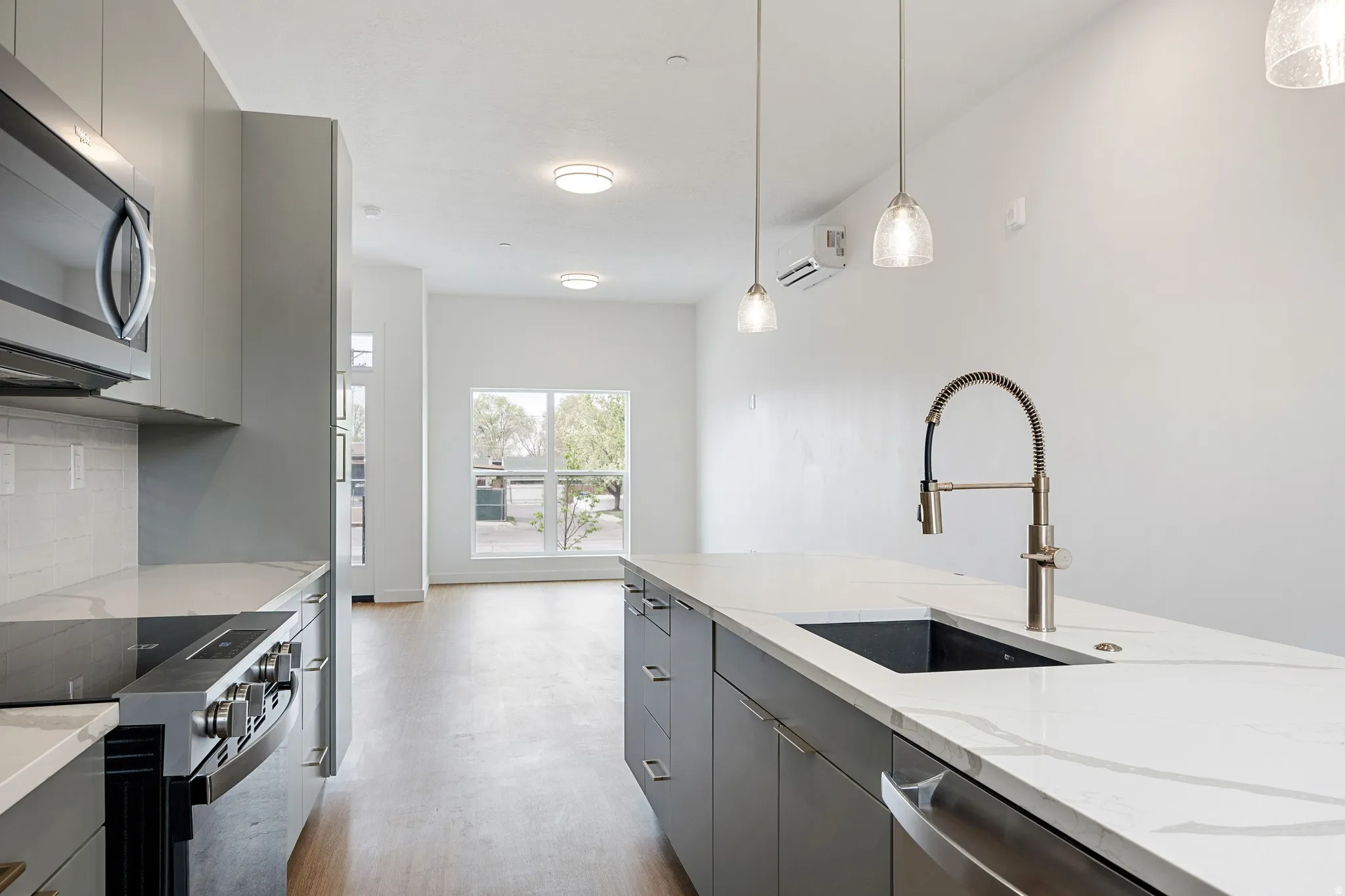 Modern kitchen featuring gray cabinetry, stainless steel appliances, and white countertops