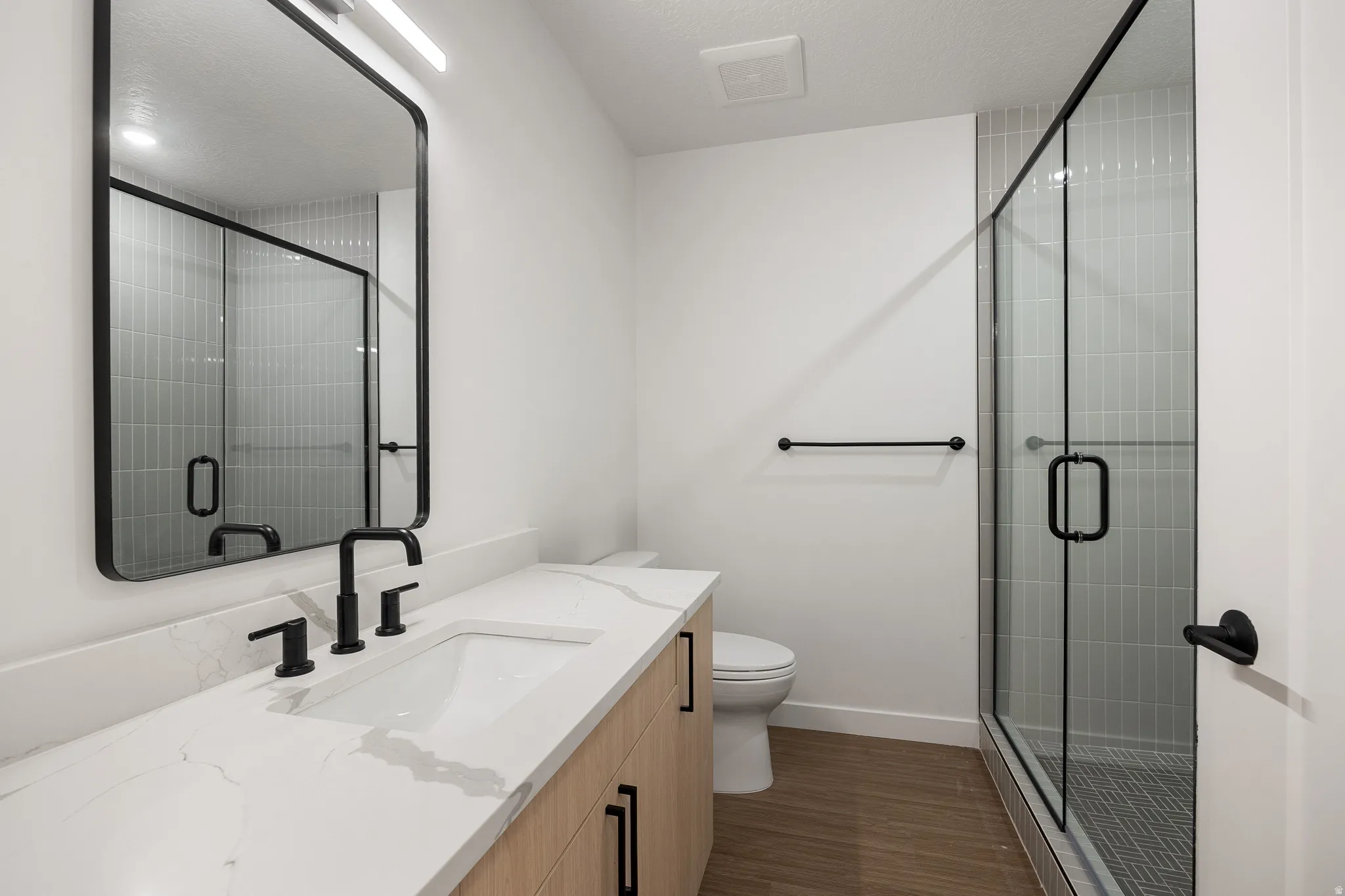 Walk-in shower with clear glass enclosure, subway tile surround, and chevron-patterned floor