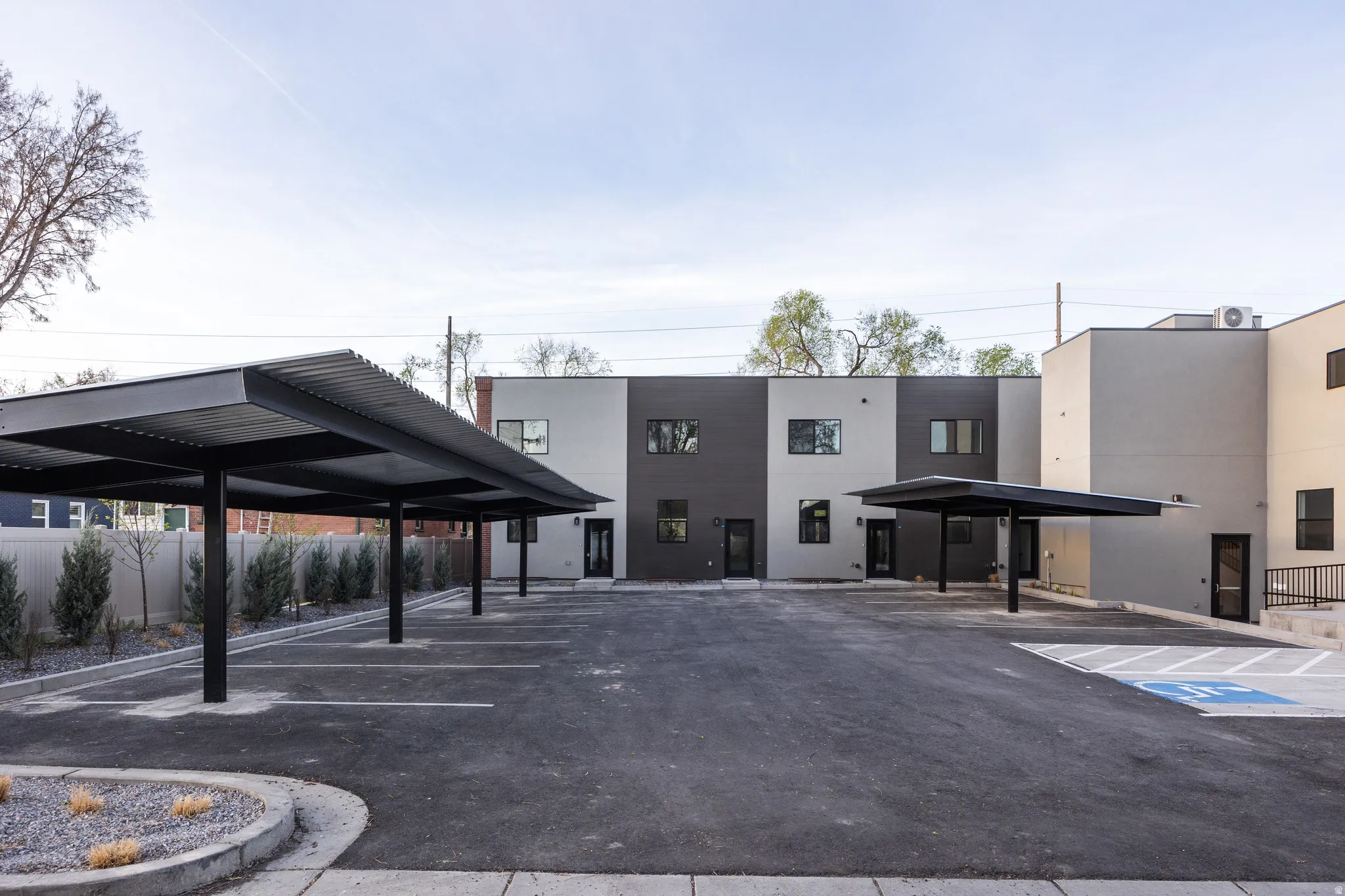 Multiple covered parking spaces, asphalt drive, modern building exterior with varied siding, and a dedicated accessible parking space