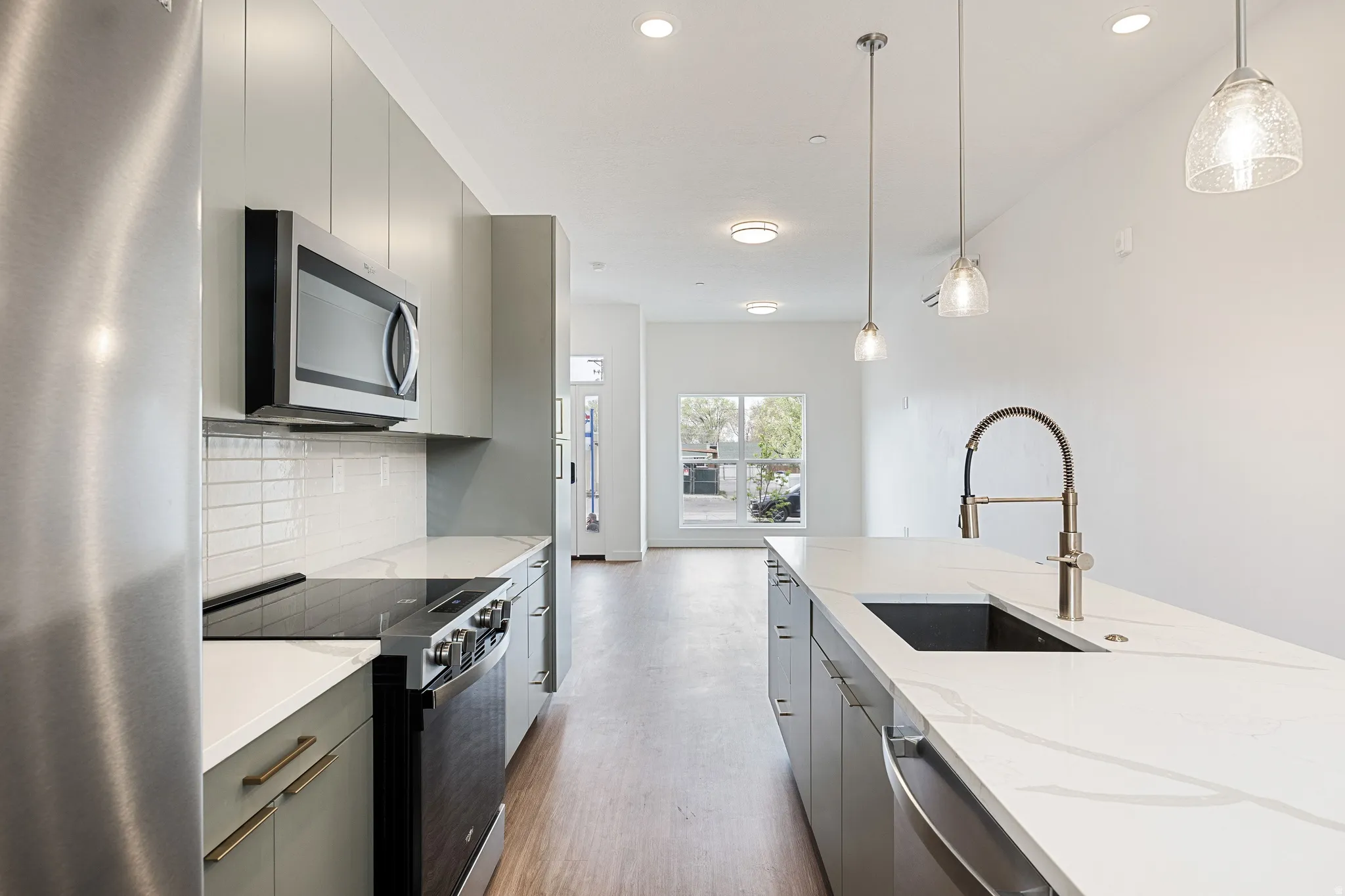 Modern kitchen featuring stainless steel appliances, stone countertops, and wood-finish flooring
