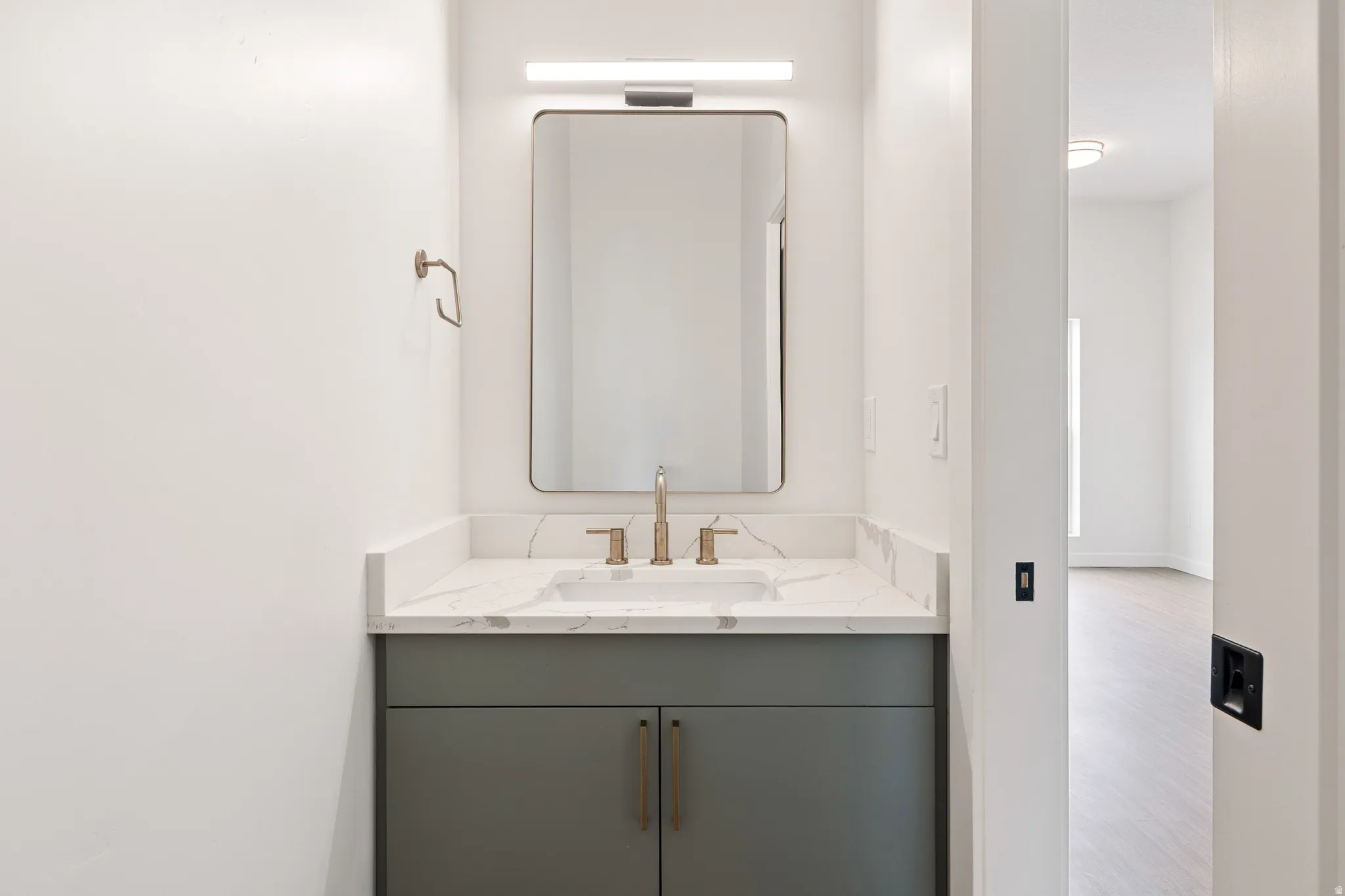 Vanity with a rectangular undermount sink, a bronze-finish faucet, and a stone-finish countertop