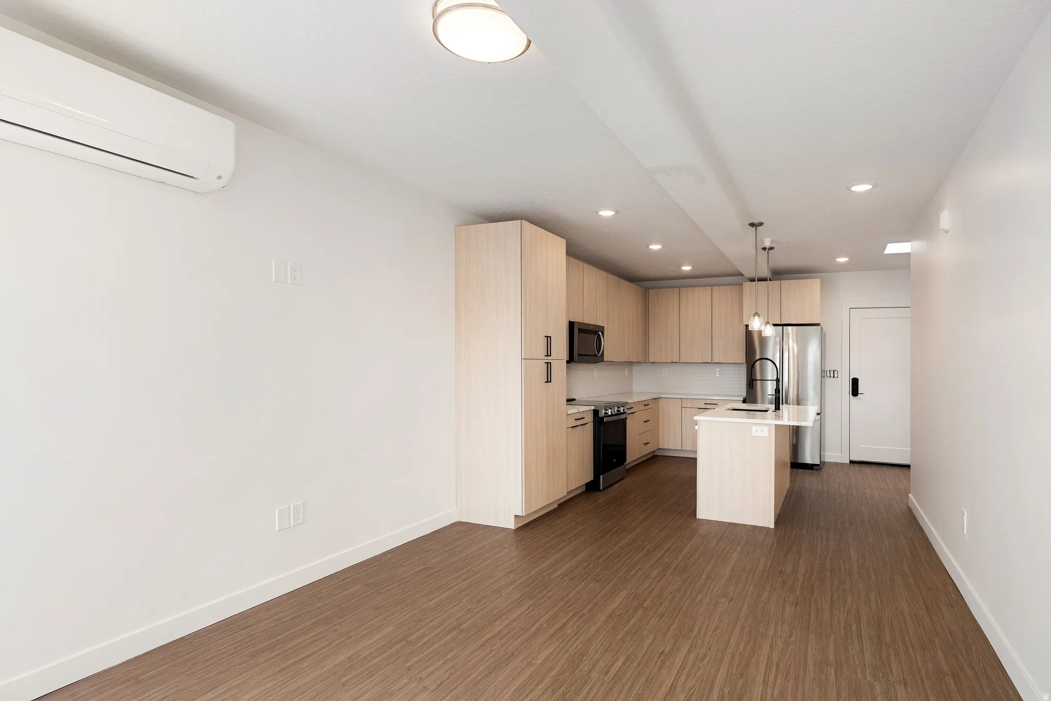 Open-concept living area featuring wood-finish flooring, recessed lighting, and a modern kitchen