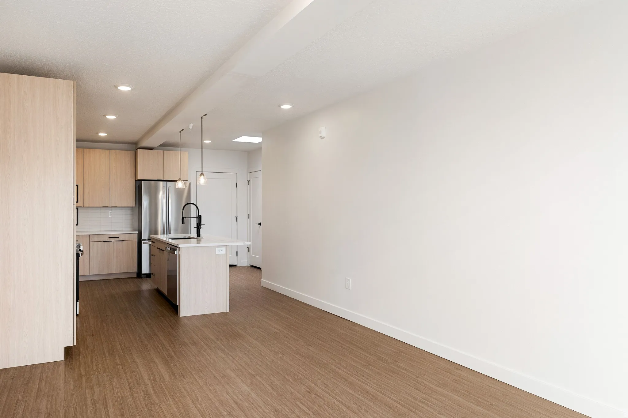 Wood-finish flooring throughout, recessed lighting, and a kitchen island with pendant fixtures