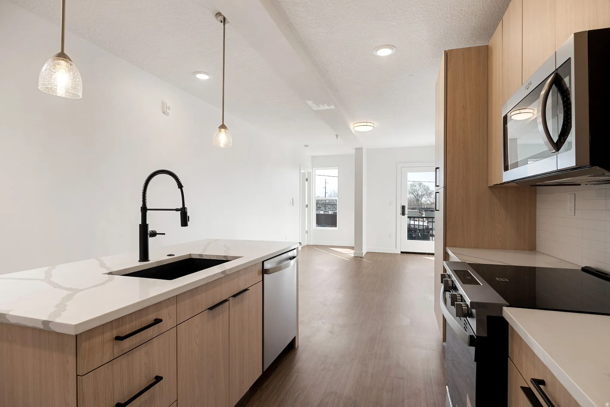 Kitchen island with a white veined countertop, black undermount sink, and matte black faucet