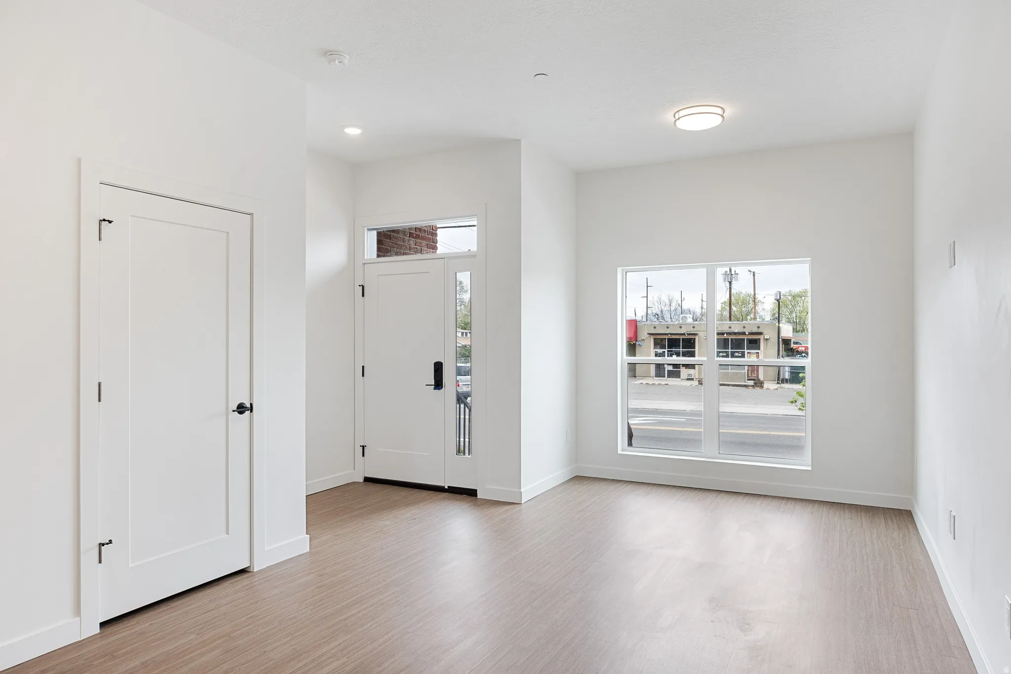 Wood-finish flooring, white walls, and a large window with white trim