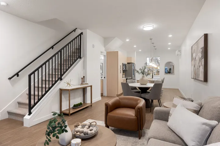 Open-concept living space featuring wood-finish flooring, recessed lighting, and a modern staircase with black metal railing