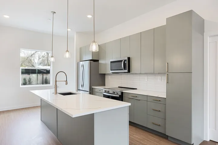 White kitchen island with a rectangular sink, modern faucet, and three pendant lights