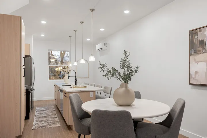 Kitchen featuring wood-finish flooring, recessed lighting, an island with pendant lights, a black gooseneck faucet, and light wood cabinetry