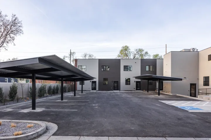 Multiple covered parking spaces, asphalt drive, modern building exterior with varied siding, and a dedicated accessible parking space
