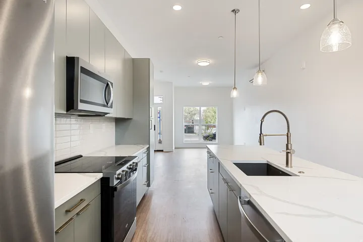 Modern kitchen featuring stainless steel appliances, stone countertops, and wood-finish flooring