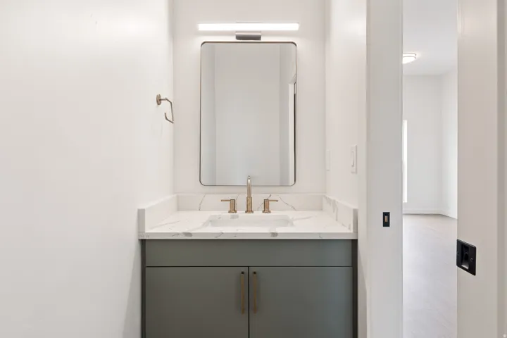 Vanity with a rectangular undermount sink, a bronze-finish faucet, and a stone-finish countertop
