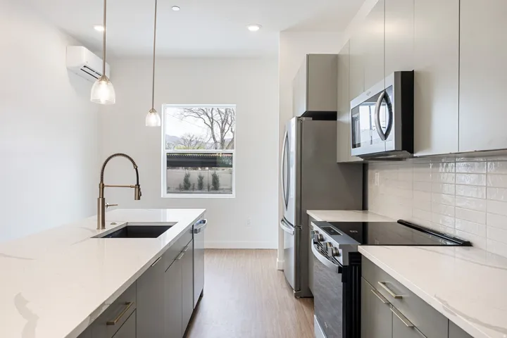 Contemporary kitchen featuring light wood-finish flooring, white countertops, gray cabinetry, and stainless steel appliances