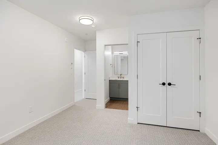 Recessed lighting, wood-finish flooring, white flat-panel doors, matte black hardware, and a vanity with an integrated sink