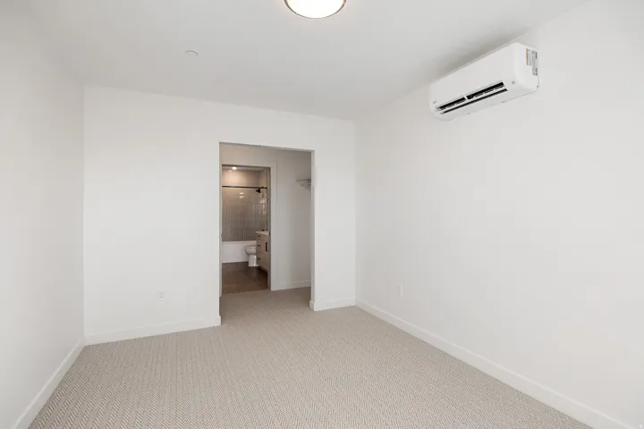 White walls with patterned carpeting and flush-mount ceiling lighting