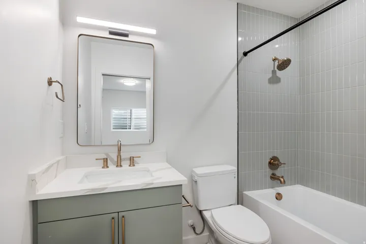 Vanity with a white countertop and integrated sink, bronze-finish faucet, and modern mirror
