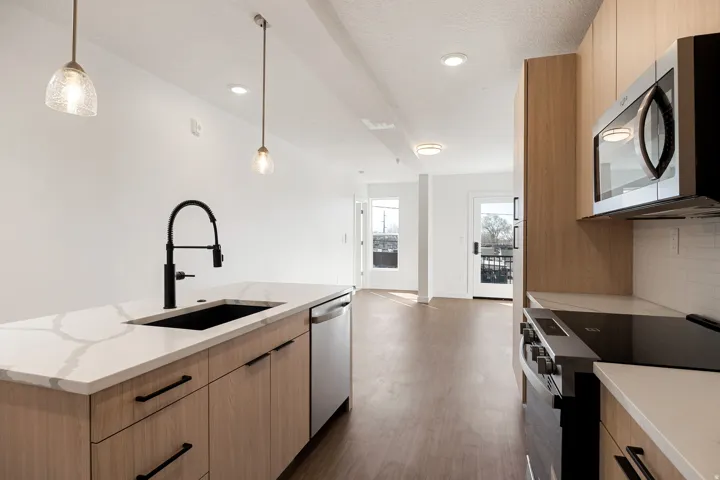 Kitchen island with a white veined countertop, black undermount sink, and matte black faucet