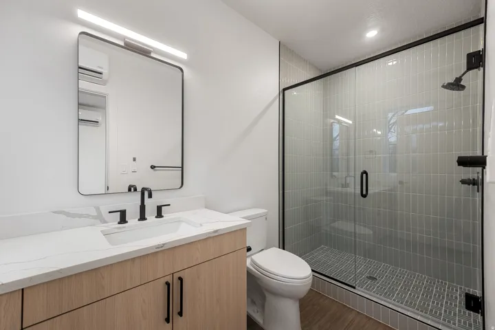 Light wood-finish vanity with a white countertop, undermount sink, and matte black fixtures