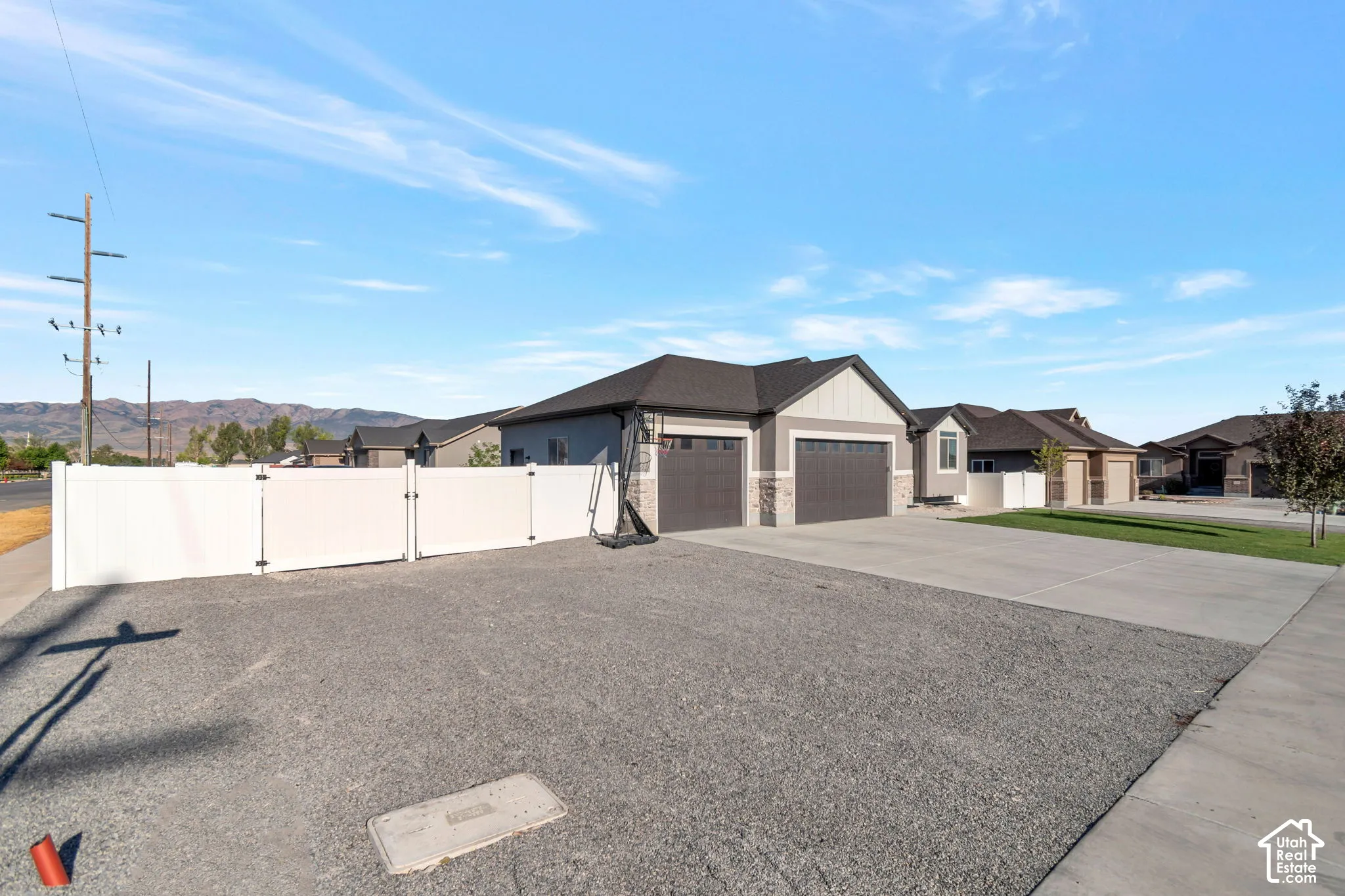 Exterior featuring a two-car garage, stone and siding facade, and a white privacy fence