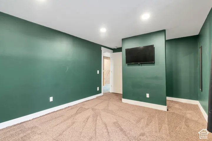Recessed lighting, dark green painted walls, neutral-toned carpeting, and a built-in wall partition