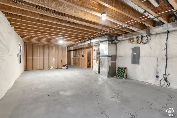 Unfinished basement with exposed ceiling joists, concrete flooring, and framed interior walls