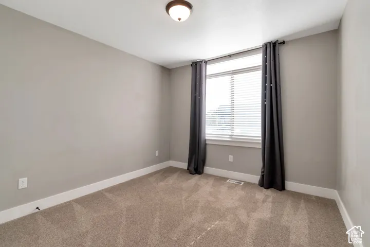 Carpeted flooring, neutral wall tones, white trim, and a window with blinds