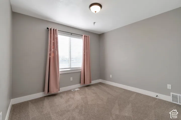 Neutral gray walls, plush carpet flooring, and a single window with white blinds