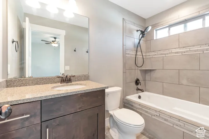Vanity with a light-toned countertop, wood-finish cabinetry, and a large wall-mounted mirror