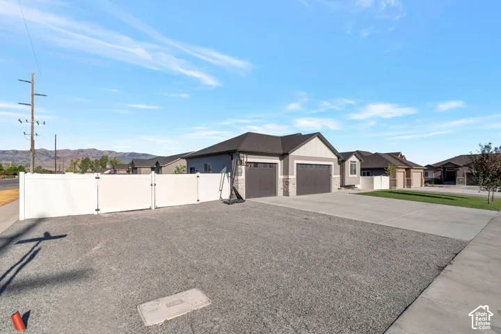 Exterior featuring a two-car garage, stone and siding facade, and a white privacy fence