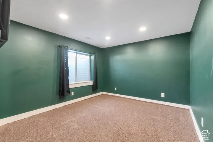 Recessed lighting illuminating the carpeted flooring and deep green walls