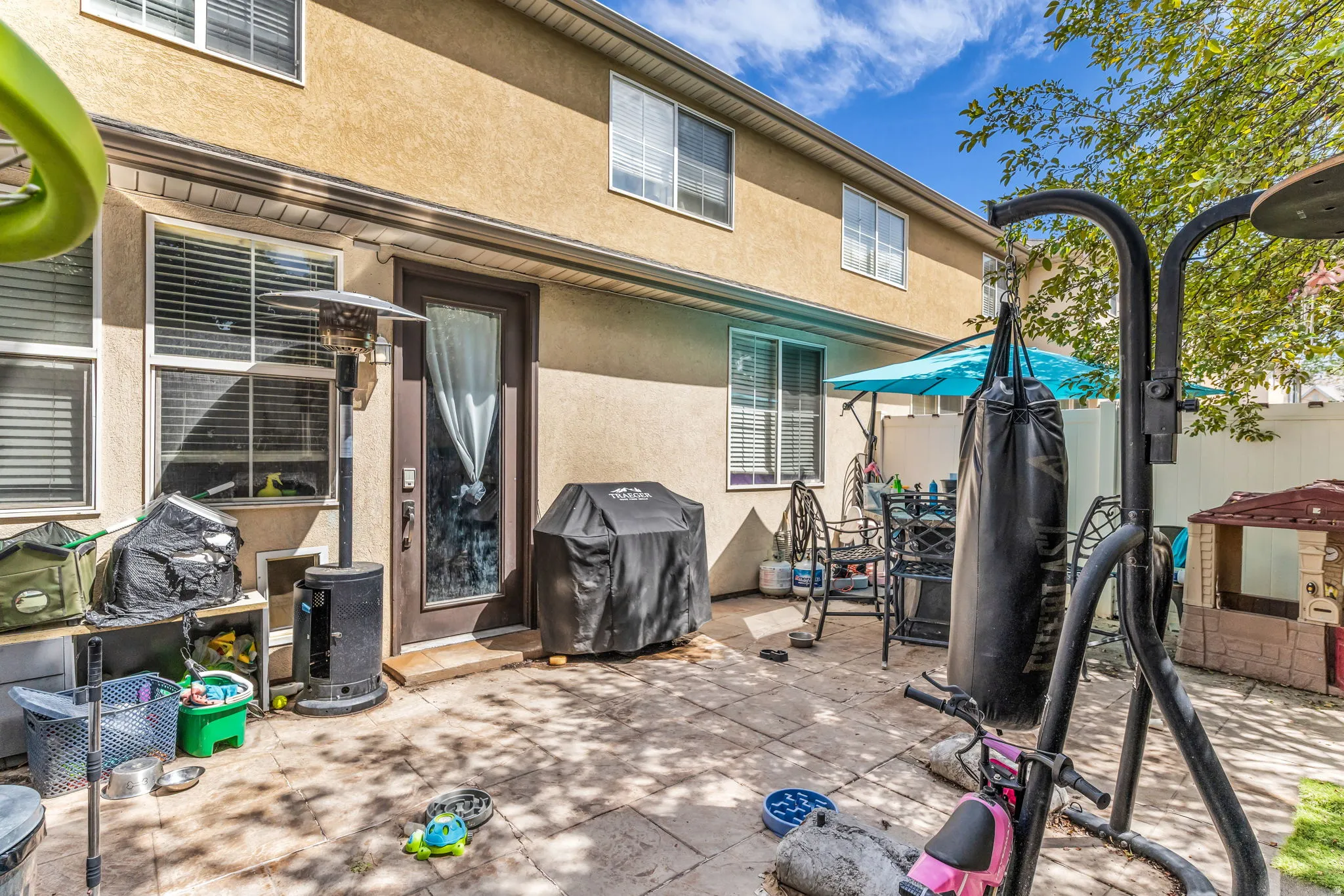 Paved patio area, stucco exterior, multiple windows, opaque door
