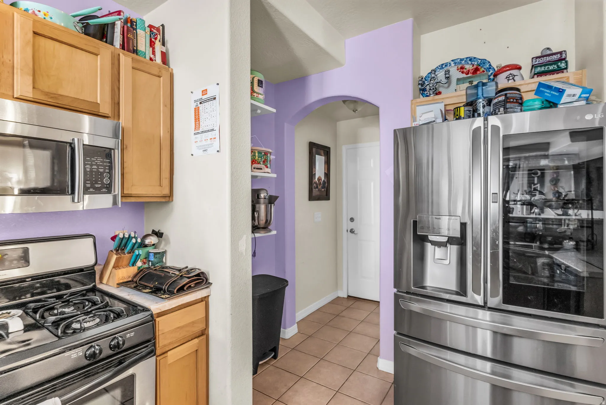 Stainless steel microwave, wood cabinetry, stainless steel range with gas burners, and a stainless steel refrigerator