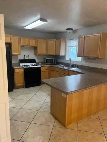 Kitchen featuring light wood cabinetry, stone-look countertops, and tile flooring