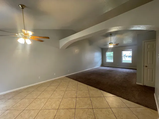 Vaulted ceilings, a tiled entry, arched architectural details, and two ceiling fans