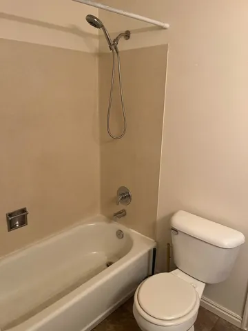 Bathroom featuring a white bathtub, chrome shower fixtures, and a white toilet