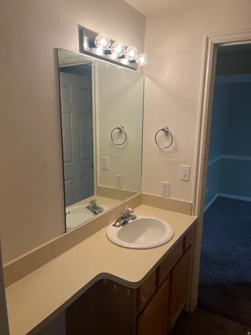 Vanity with an integrated sink, laminate countertop, mirrored wall, and overhead lighting fixture