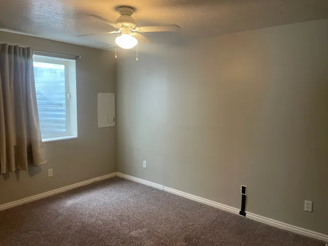 Plush carpeting, neutral wall color, white window trim, and a ceiling fan with integrated lighting
