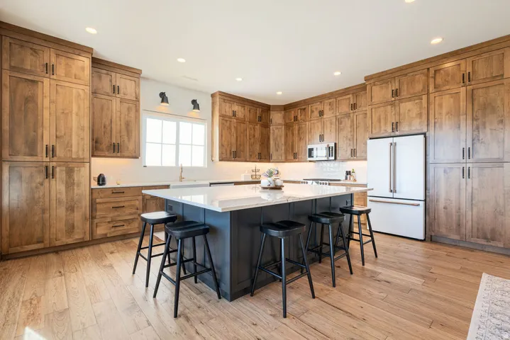 Spacious kitchen featuring extensive wood-finish cabinetry, a large kitchen island with a light-toned countertop, and recessed lighting