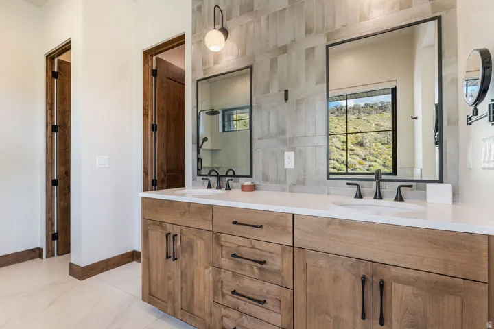 Dual wood-finish vanities with white countertops, undermount sinks, and matte black fixtures