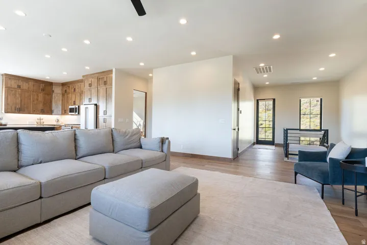 Open-concept living area featuring recessed lighting, wood-finish flooring, and a kitchen with wood cabinetry and stainless steel appliances