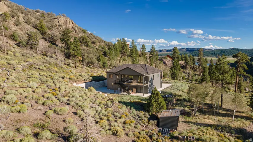 Two-story property with a dark-pitched roof, upper-level deck, and lower-level patio