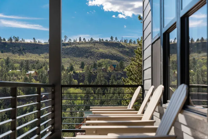 Balcony with horizontal metal railings, siding exterior, large windows, and a prominent hillside landscape