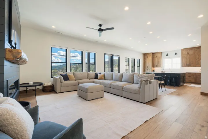 Open-concept living area featuring wood-finish flooring, a contemporary fireplace, recessed lighting, and a modern ceiling fan